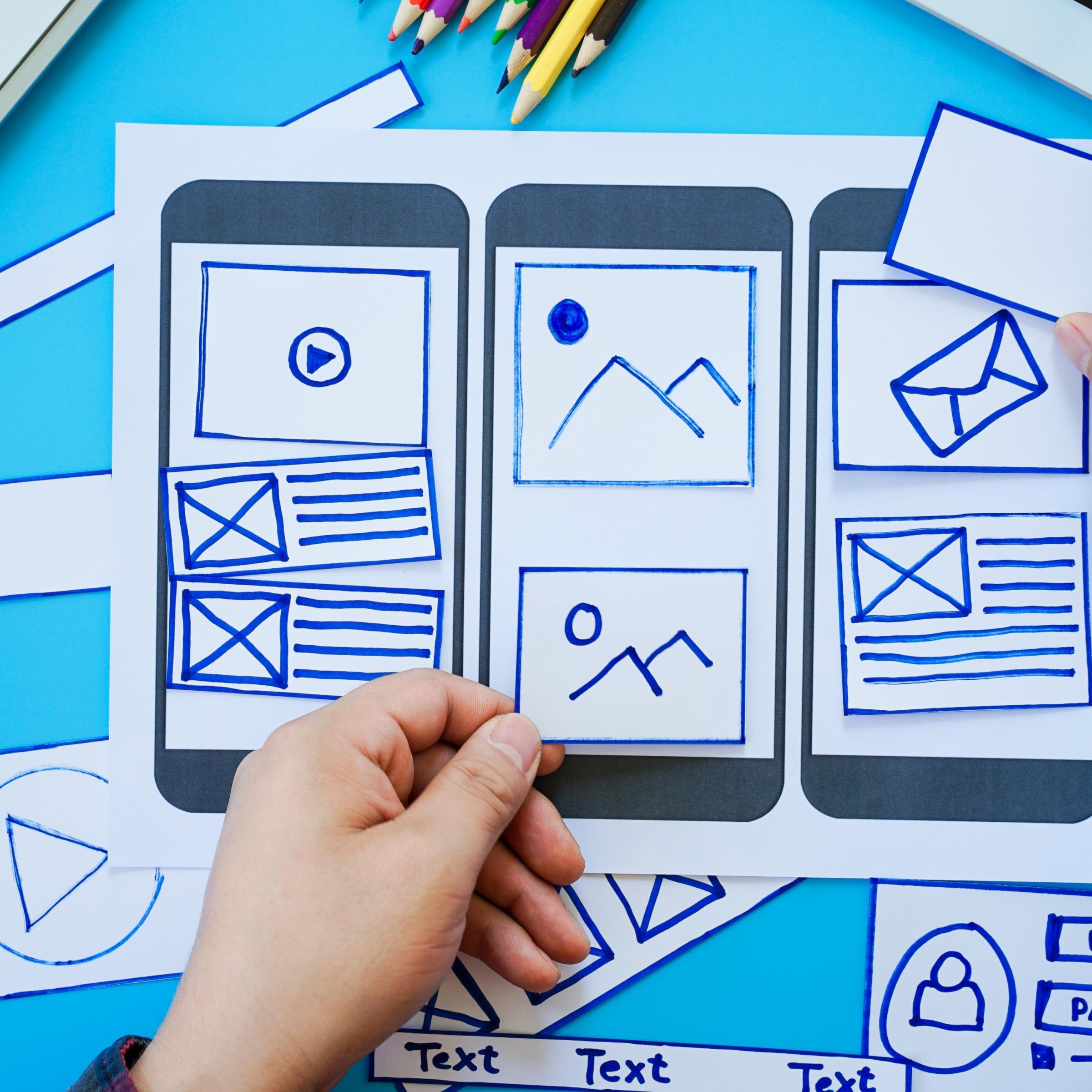 Mobile App Services 2 Mobile app developer holding a drawing of a cell phone represents the mobile app development process.