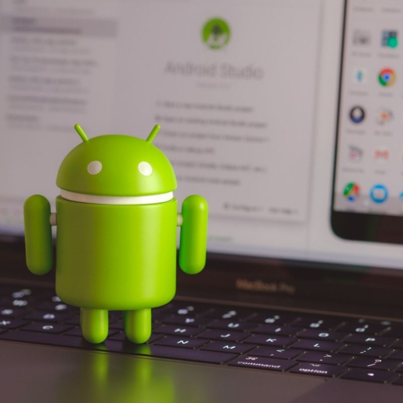 Android app development figurine sitting on a laptop keyboard.
